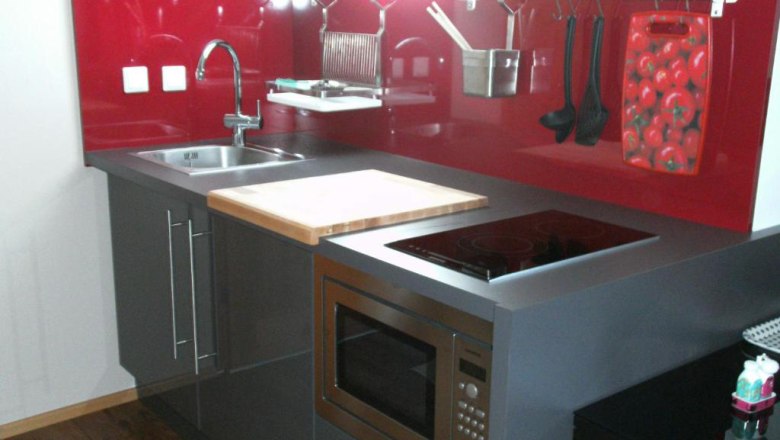 Country house Rossatz, © Familie Schlager Modern kitchen with red splashback, sink, stove and microwave.