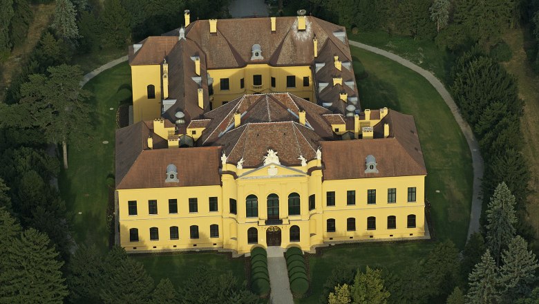 Eckartsau Castle aerial view 2010, © ÖBf AG Aerial view of Eckartsau Castle, surrounded by trees and gardens.
