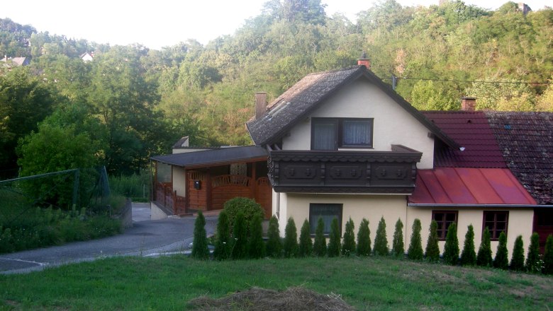 Private room Gruber, © Siegfried Gruber A house with a balcony and garden, surrounded by trees and hills.
