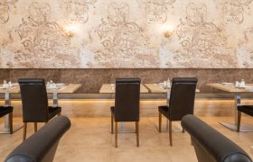 Breakfast buffet, © Hotel Unter den Linden An elegant restaurant with laid tables and stylish wall decorations.