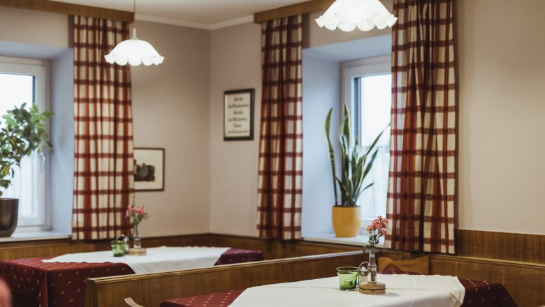 Inviting pub, © Niederösterreich Werbung/David Schreiber Cozy pub with wooden furniture, checkered curtains and decorated tables.
