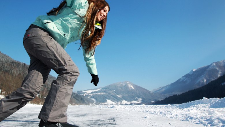 Ice skating on Lake Lunz, © weinfranz.at A person skates on a frozen lake with snow-covered mountains in the background.