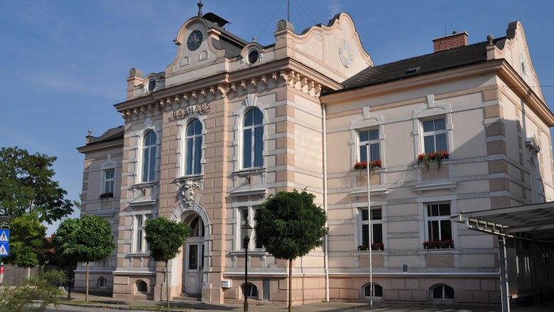 Felixdorf Town Hall, © Spiderman183 The town hall of Felixdorf, a historic building with a clock tower and ornate windows, surrounded by trees and a street in the foreground.