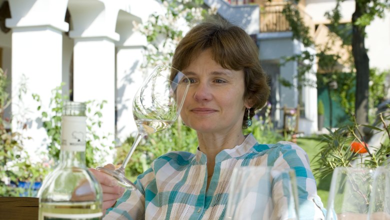 Hostess, © Michael Himml Woman with wine glass in the garden, bottle in the foreground.