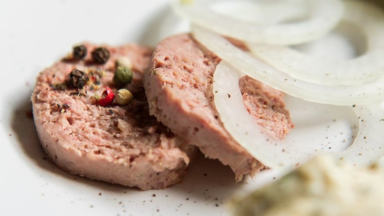 Heurigen snack, © Weinberghof Ilkerl Close-up of slices of sausage with peppercorns and onion rings on a plate.