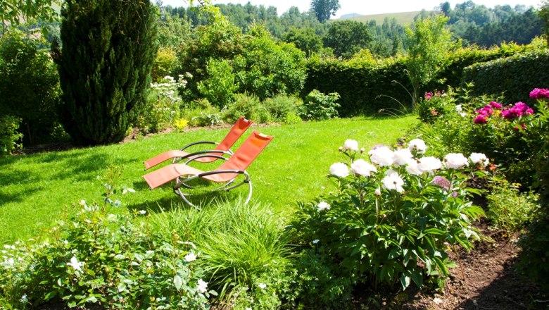Bognerhof nursery, © Bognerhof Garden with two red deckchairs and blooming flowers.