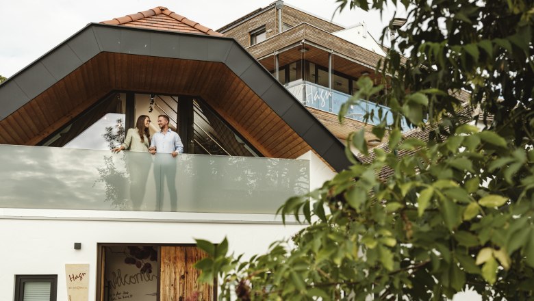 Winery Hagn Kellerstöckl, © Weinviertel Tourismus GmbH A modern building with a couple on the balcony, surrounded by trees.