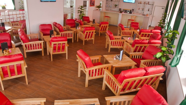 Lounge, © Winrooms Betriebs GmbH A lounge with red armchairs and wooden tables on a wooden floor.