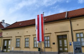 Exterior view of the Neunkirchen Municipal Museum, © Vanessa Staudenhirz Exterior view of the Neunkirchen Museum with Austrian flag and information sign.