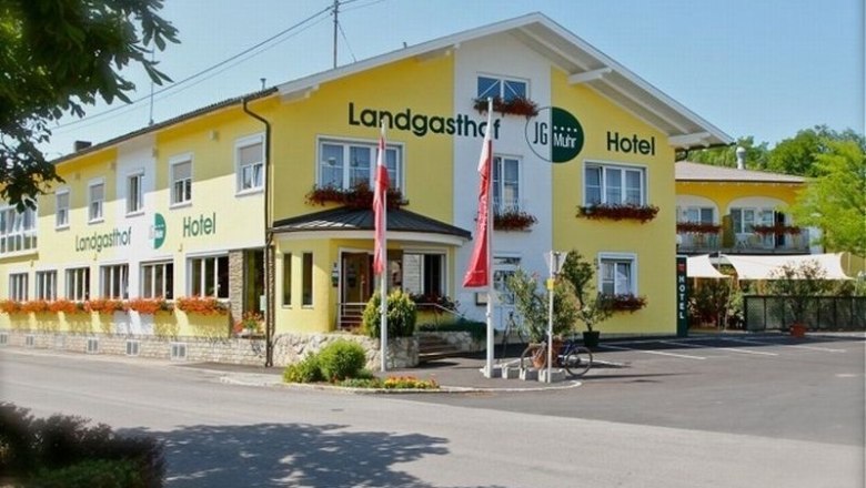 Main house, © Landgasthaus Hotel Muhr Yellow country inn hotel with flower boxes and Austrian flags.