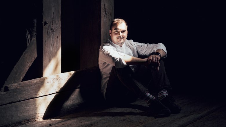 Weinviertel meets England in Samuel Pope's kitchen, © Niederösterreich Werbung/Julius Hirtzberger Man in white shirt sitting in the shade on wooden floor.