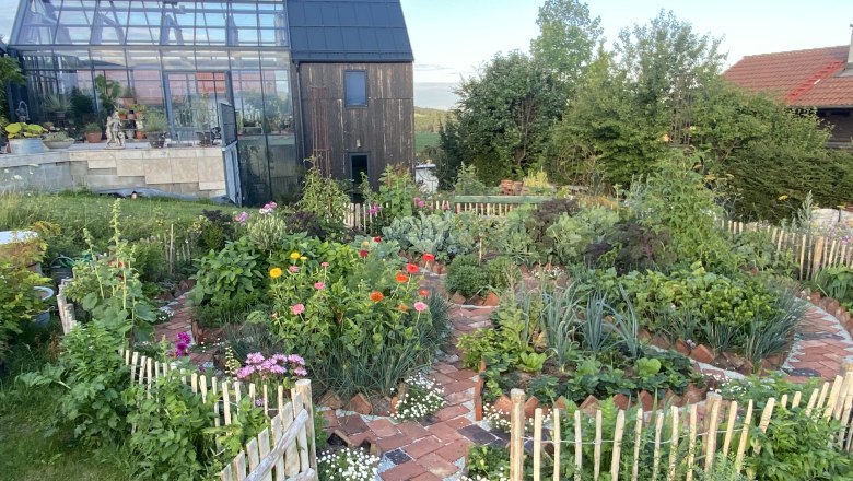 View of the "Fernery" - the glass house in the Ecolution.Lab, © Bernd Hochwartner A glass house from the outside in the Ecolution.Lab with a colorful garden in the foreground.