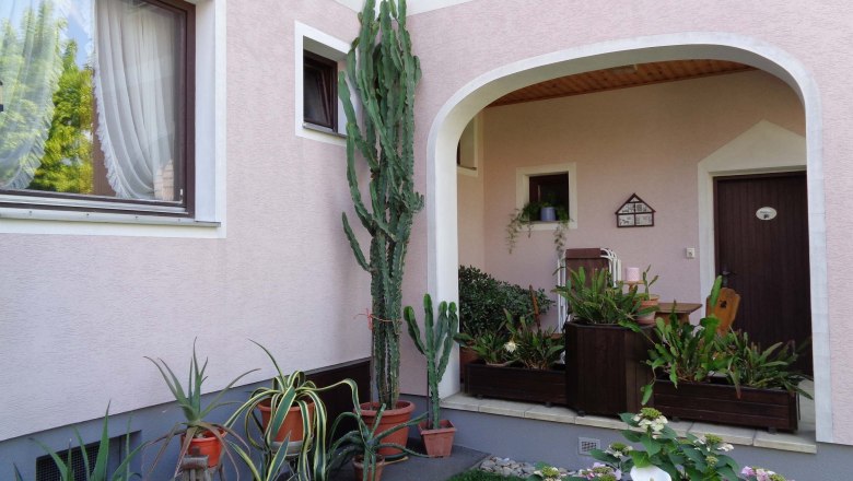 Guesthouse Schlossblick, entrance, © Marschik Inner courtyard with a view of a pink façade and many potted plants and windows.