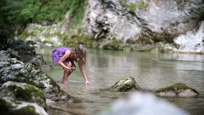 Ötscher Tormäuer Nature Park, © Mostviertel Tourismus, weinfranz.at A child in a purple dress plays in a clear stream, surrounded by rocks and green nature.