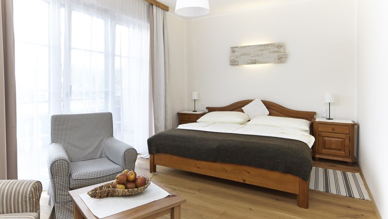 Room Krumbacherhof, © Wiener Alpen / Bene Croy Bright room with double bed, armchair and table with fruit bowl.