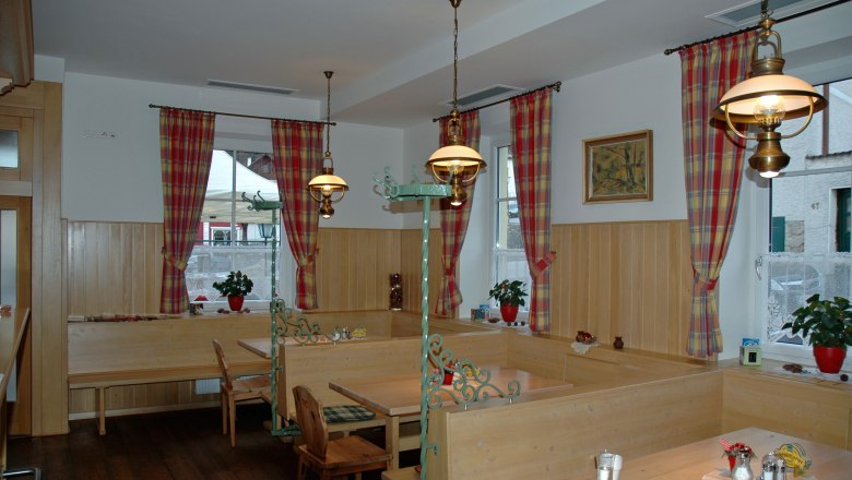 Hotel Zur Alten Schule, © Viregro Capital Gmbh Cozy dining room with wooden furniture and checkered curtains.