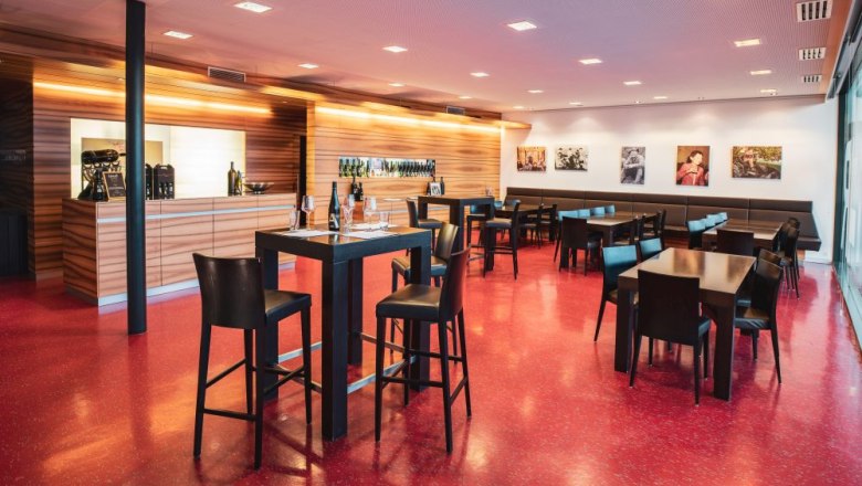 Tasting room, © Michael Parak Modern tasting room with wooden counters, red floor tiles and black tables and chairs.