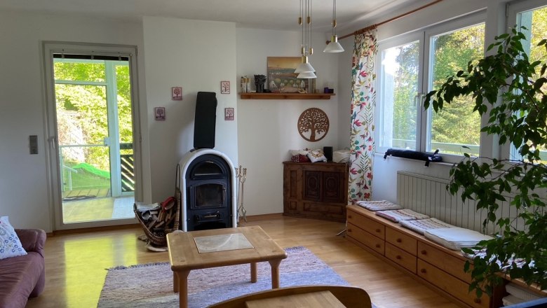 Living room, © Wiener Alpen A cozy living room with wood-burning stove, wooden furniture and large windows with a view of the greenery.