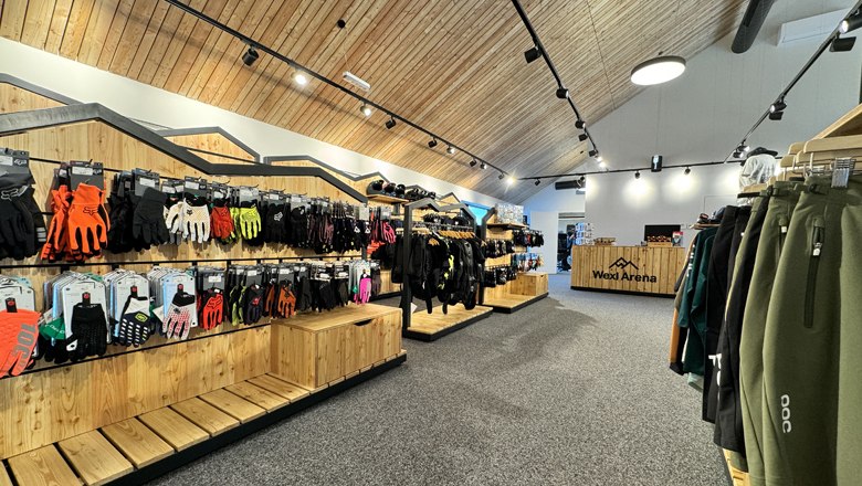 "Base station" for all visitors, © Wexl Arena St. Corona am Wechsel Interior view of a sports store with wooden shelves and sportswear.