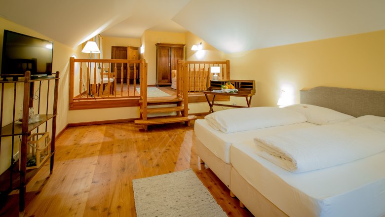 Deluxe double room with garden view, © Schlossschenke A cozy hotel room with a double bed, wooden floor and a small table with fruit.