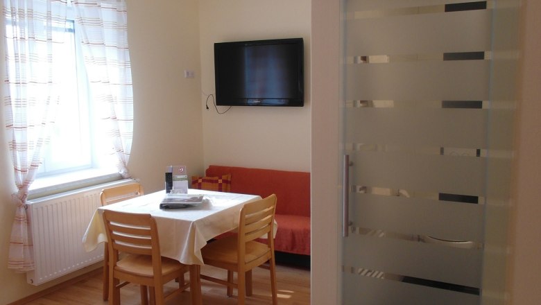 Dining area in the room at the Lugerhof, © Lugerhof Bright room with dining area, table, chairs, bed and flat screen TV.