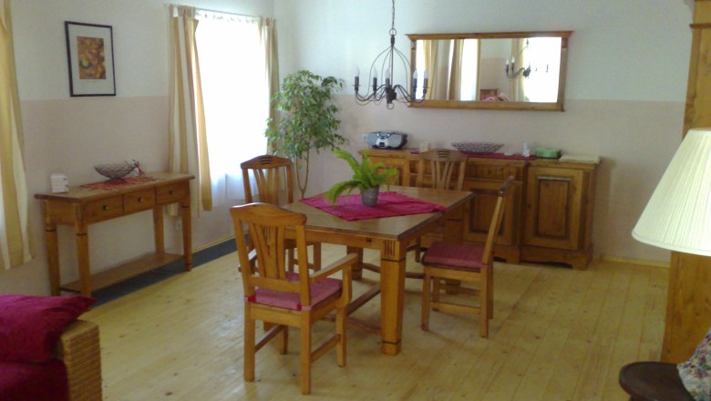 Vacation home to the old smithy Heidi Koch, © Ferienhaus Koch Cozy living room with wooden furniture, dining table, chairs and plants.