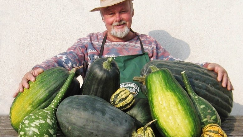 ernte-51-2008_klein_c_f-kreiner, © Friedrich Kreiner Man in a straw hat presents large pumpkins on a table.