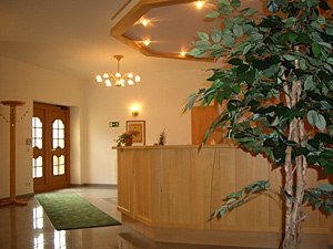 Gasthof Kögl 'Zum Liederfürst', © Gasthof Kögl Zum Liederfürst Reception area of an inn with wooden counter and plant.