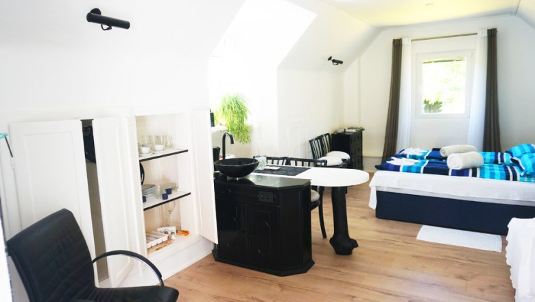 Vacation home interior view, © Maria Theresia Schwarz-Mach Interior view of a bright vacation home with bed, table, chairs and kitchenette.