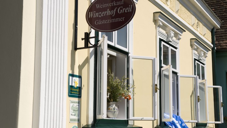 Winzerhof & Guesthouse Greil, © M. Greil Facade of a yellow building with open windows and a sign 'Winzerhof Greil'.