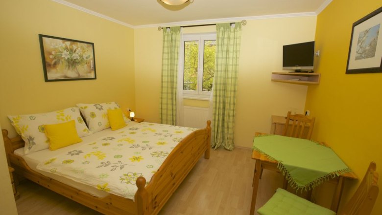 Guesthouse Ebner, © Familie Ebner Cozy guest room with double bed, yellow walls and small table.