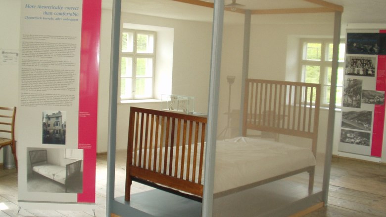 Wittgenstein exhibition, © Gemeinde Trattenbach Exhibition room with a bed behind glass and information boards.