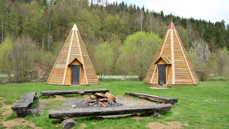 Tipis - Gaul, © Karin Spiesmaier Two wooden tepees on a meadow in front of a forest.