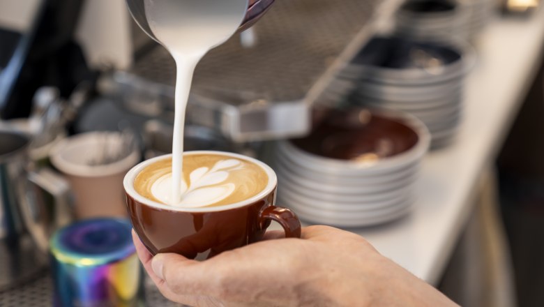 Coffee hall Semmering, © wieneralpen_herbst Close-up of a hand pouring latte art into a coffee cup.