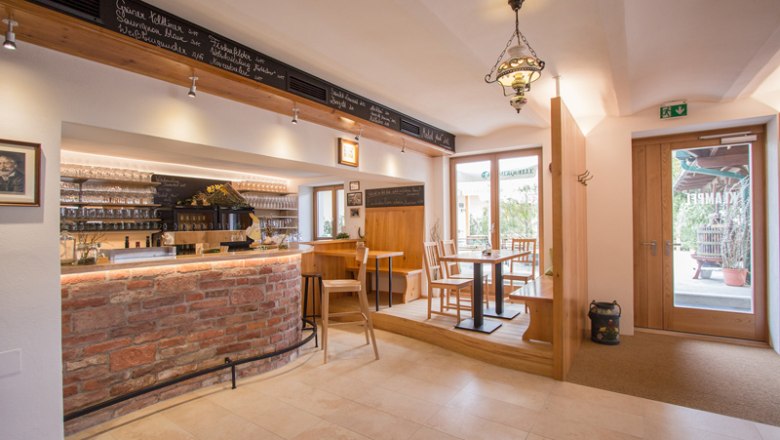 Wine bar Weinbau Klampfl, © hamp.at Interior view of a cozy wine bar with wooden furniture and brick counter.