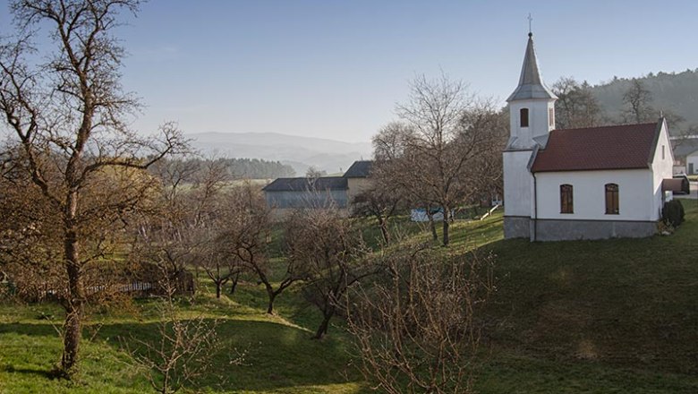 View from the balcony, © © Fam. Wilhelm Landscape with church and trees under a clear sky.