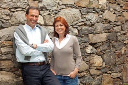 Winemaker, © Weingut Prager A man and a woman stand smiling in front of a stone wall.
