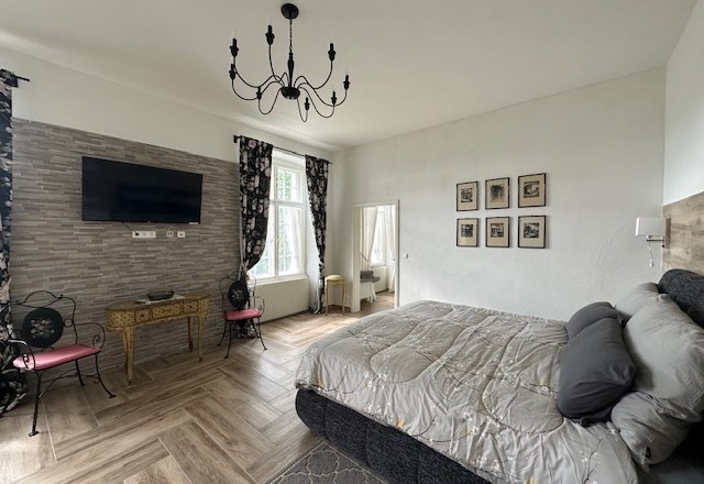 Deluxe room, © Schloss Gut Ziegersberg Elegant hotel room with large bed, chandelier, TV and decorative elements.