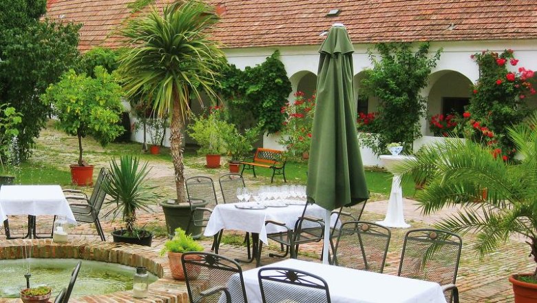 Inner courtyard, © Genießerhof Haimer An idyllic courtyard with tables, chairs, plants and a fountain.