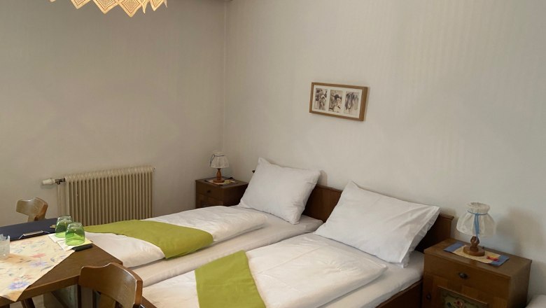 Double room, © Wiener Alpen Cozy double room with two single beds, wooden furniture and a decorative lamp.