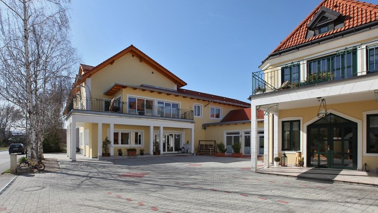 Winzerhof exterior view, © Winzerhof Achau Exterior view of a yellow vineyard with red roofs and a paved courtyard.