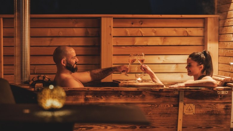 Outdoor bathtub, © Chalaalets Two people in a wooden bathtub outdoors, clinking glasses of wine.