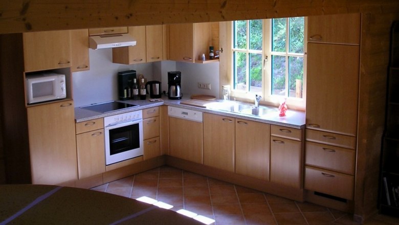 Kitchen, © Daniel Fries Modern kitchen with wooden cupboards, stove, sink and window.