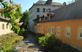 Bread and Mill Museum, © Brot- und Muehlenmuseum Historic building with stream and blossoming tree in the foreground.