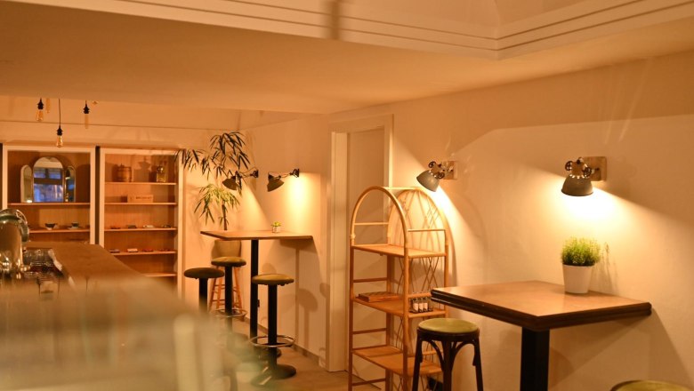 BREADLEY BISTRO, © Marek Safranek Interior view of a cozy café with wooden furniture and warm light.