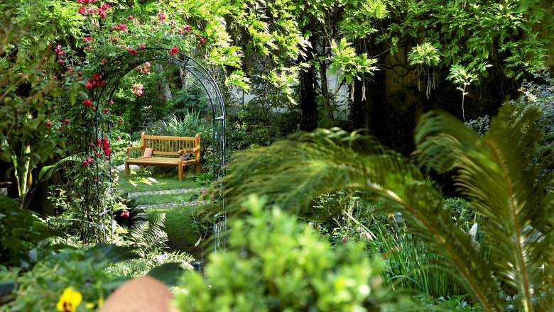 Martina and Haimo Ungersböck show garden, © Natur im Garten/Alexander Haiden An idyllic garden with a wooden bench under a rose arch.