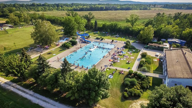 Seefeld-Kadolz leisure center, © © Marktgemeinde Seefeld-Kadolz Aerial view of an outdoor pool with swimming pool, slide and sunbathing area, surrounded by trees and fields.