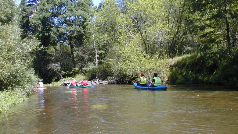 Canoe, © famreisen People paddling in canoes on a river surrounded by trees.