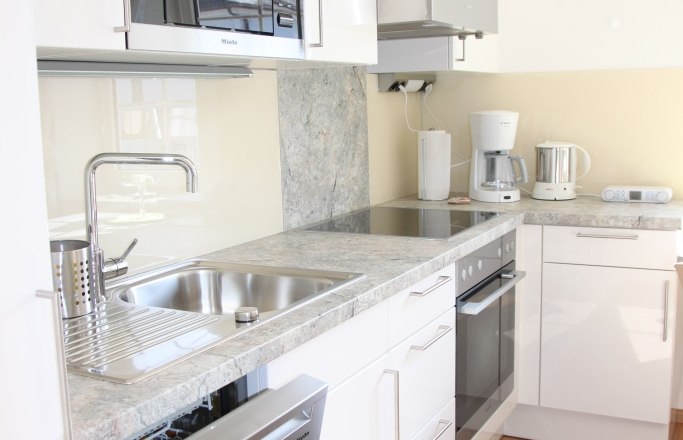 Old gatehouse, © © Elisabeth Hofer Modern kitchen with white cupboards, sink, dishwasher, microwave and coffee machine.