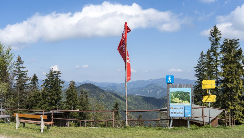 Viewpoint at the Öhler refuge, © Wiener Alpen, Franz Zwickl Viewpoint with bench, red flag and signposts in front of a mountain landscape.